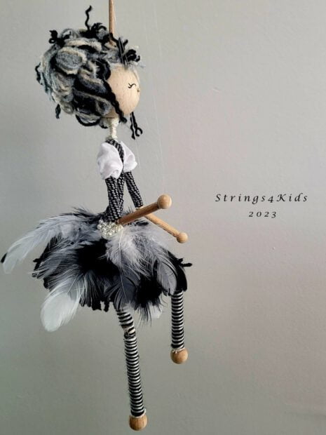 OOAK Marionette Pop Meisje in Zwart-Wit Jurk. De jurk is rijkelijk versiert met zwart met witte veren en een parel hartje. Deze marionet heeft zwart witte haren opgestoken in een knot.